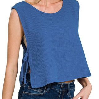 Woman wearing a blue sleeveless top with a plain background